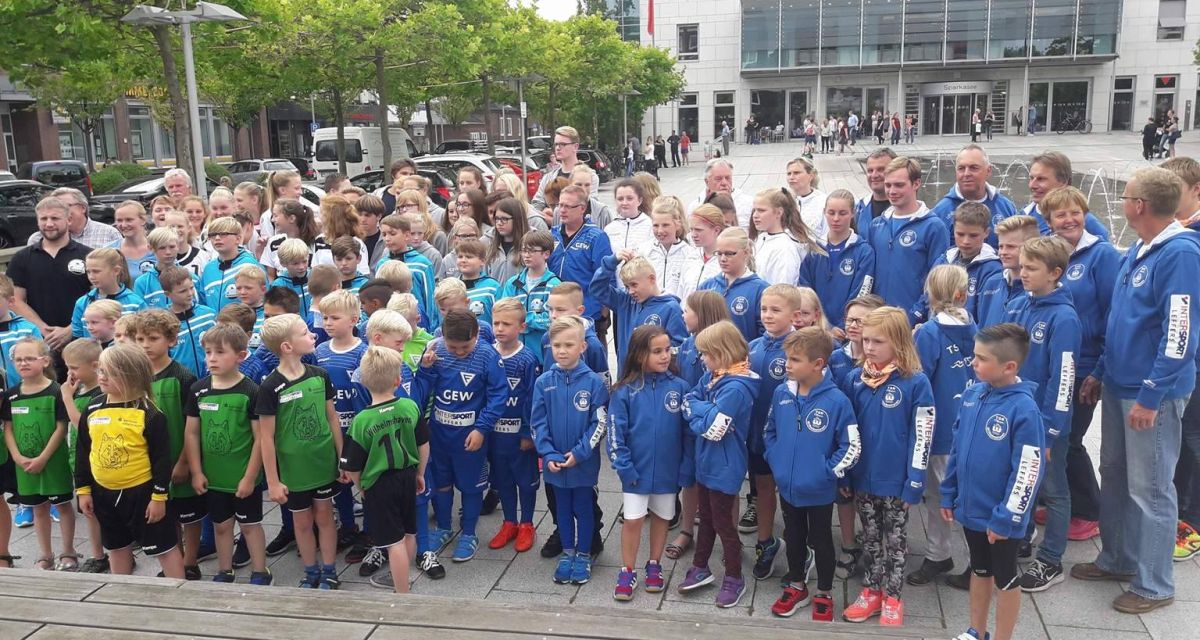 Trikotoffensive Wilhelmshaven: Kinder und Jugendliche in Sportdress stehen gemeinsam mit Erwachsenen auf dem Vorplatz der Sparkassenzentrale in Wilhelmshaven am Theaterplatz.