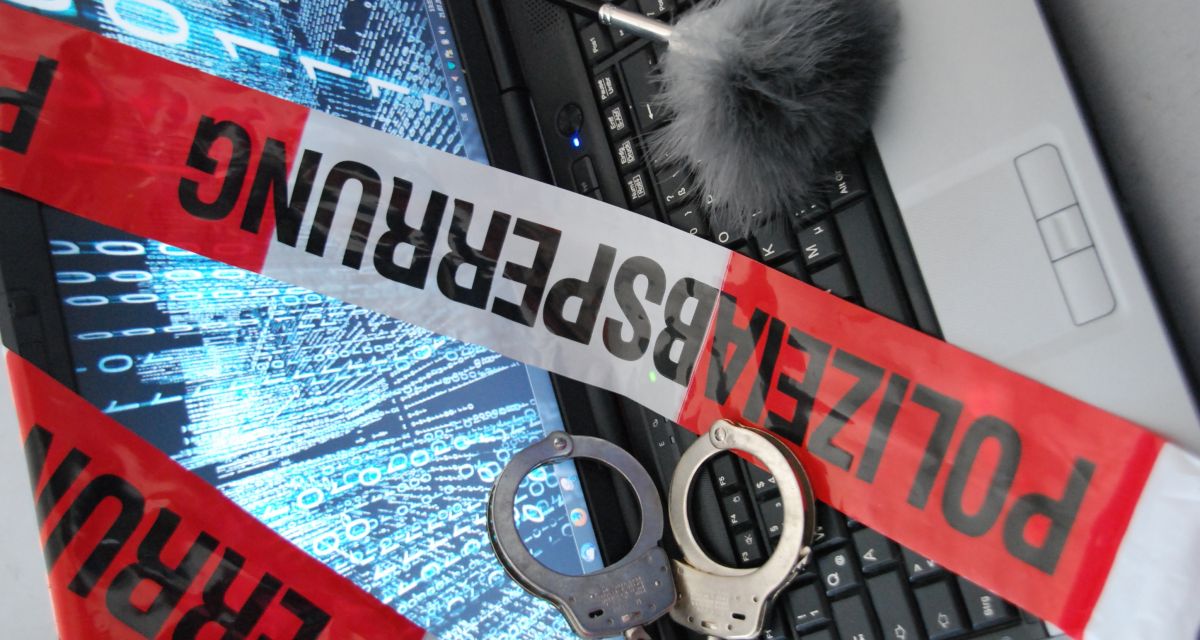 Man sieht einen Computer und ein Polizeibanner