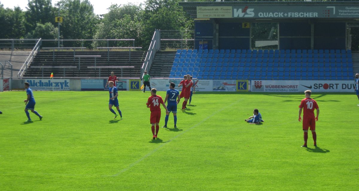 Fußballspieler in roten, beziehungsweise roten Trikots spielen auf Rasen Fußball.