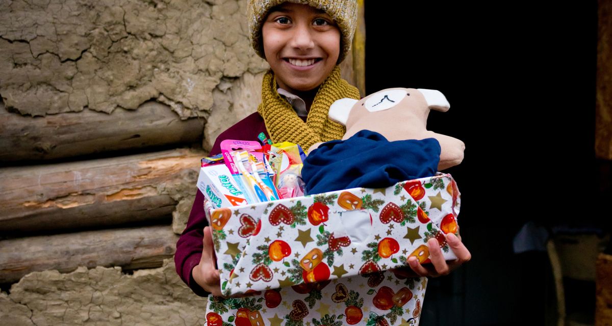 KInd mit Mütze haält Geschenk