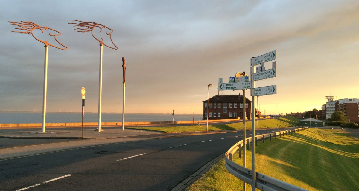 Zu sehen ist  Straße, Wiese und Himmel am Südstrand in Wilhelmshaven. 