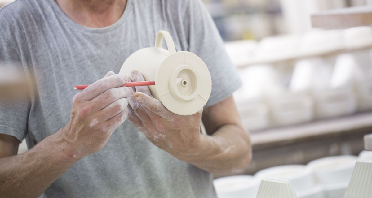 Zu sehen ist ein Mann, der einen Porzellanfilter formt. 