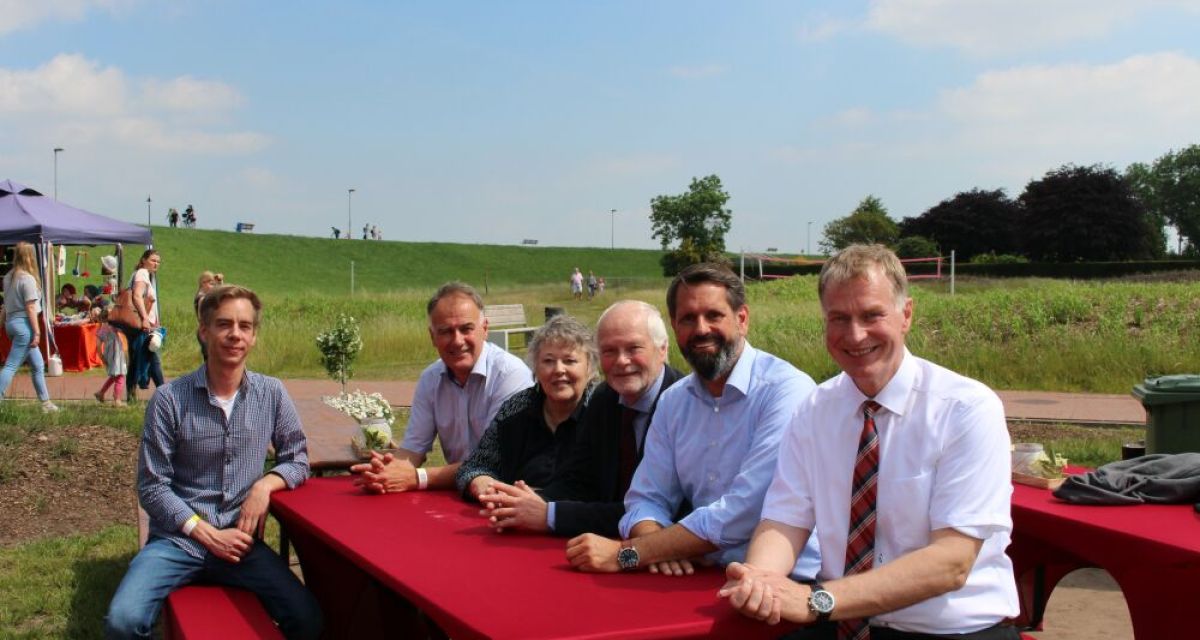 sechs Menschen an einem roten Tisch vor dem Deich