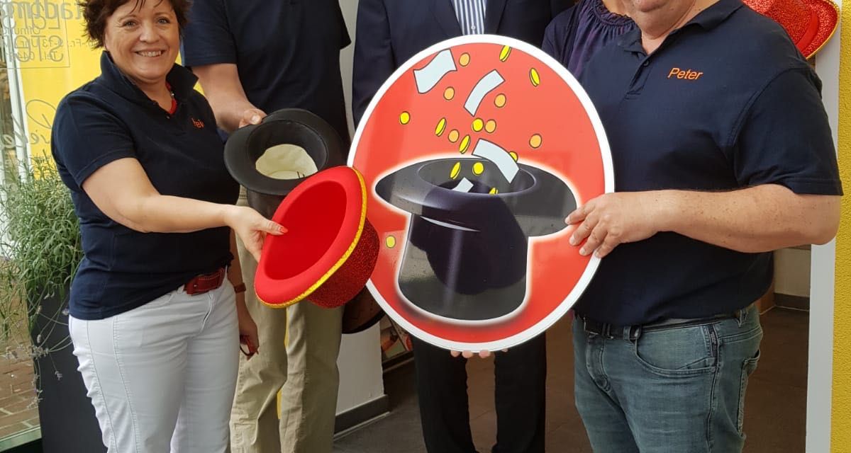 Die Organisatoren vom Schortenser Klinkerzauber halten ein Schild mit einem Hut und Geld.