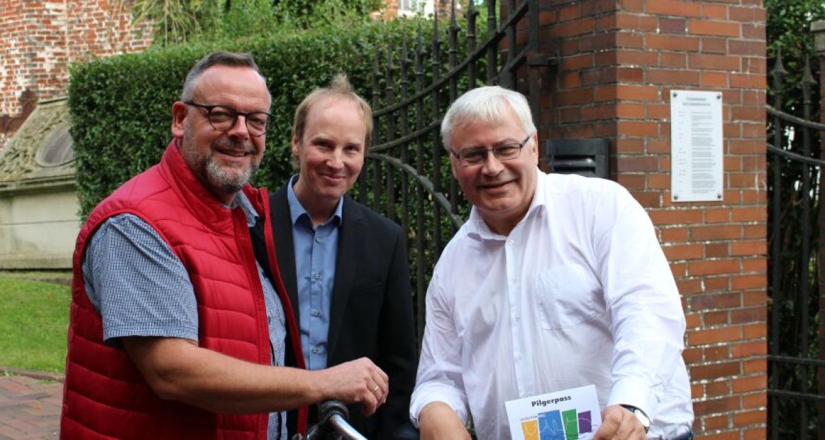 Drei Männer mit Fahrrad vor Kirche