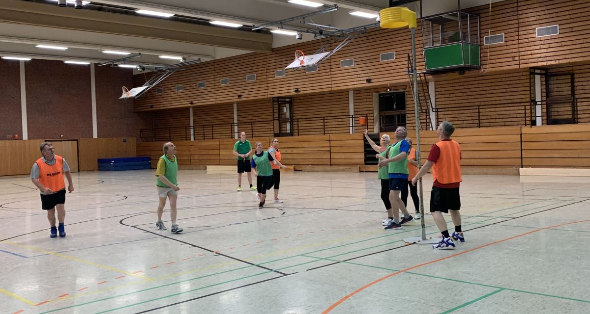 Mehrere Menschen stehen in einer Turnhalle und spielen Korfball.