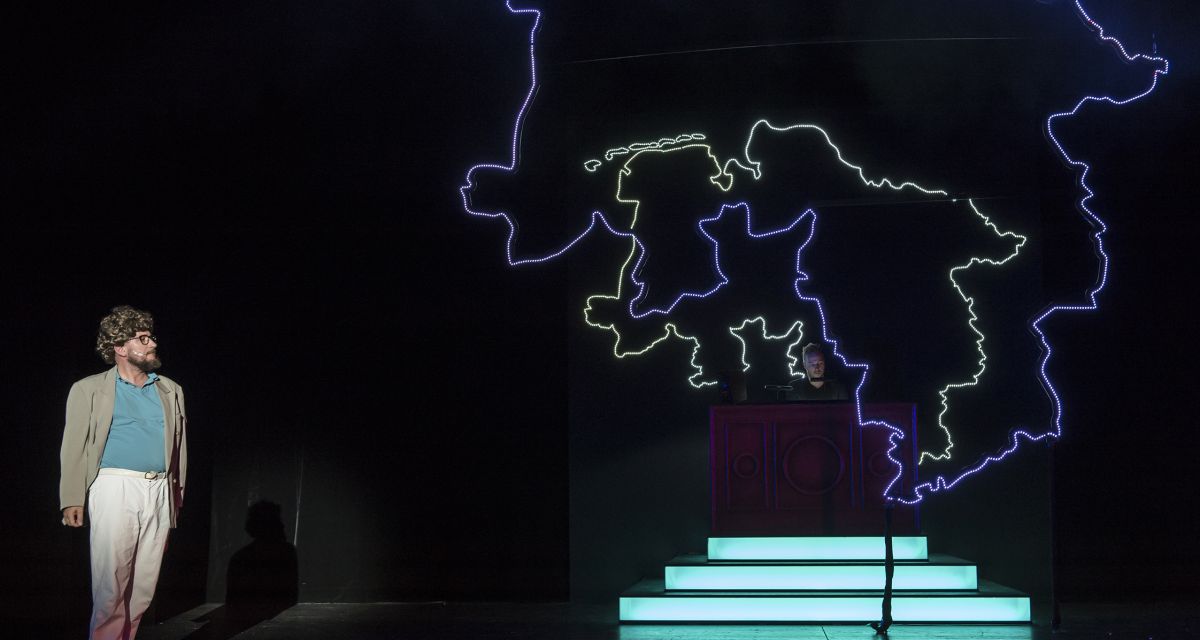 Ein Mann steht auf einer dunklen Bühne. Neben ihm sind mehrere Umrisse des Bundeslandes Niedersachsen.