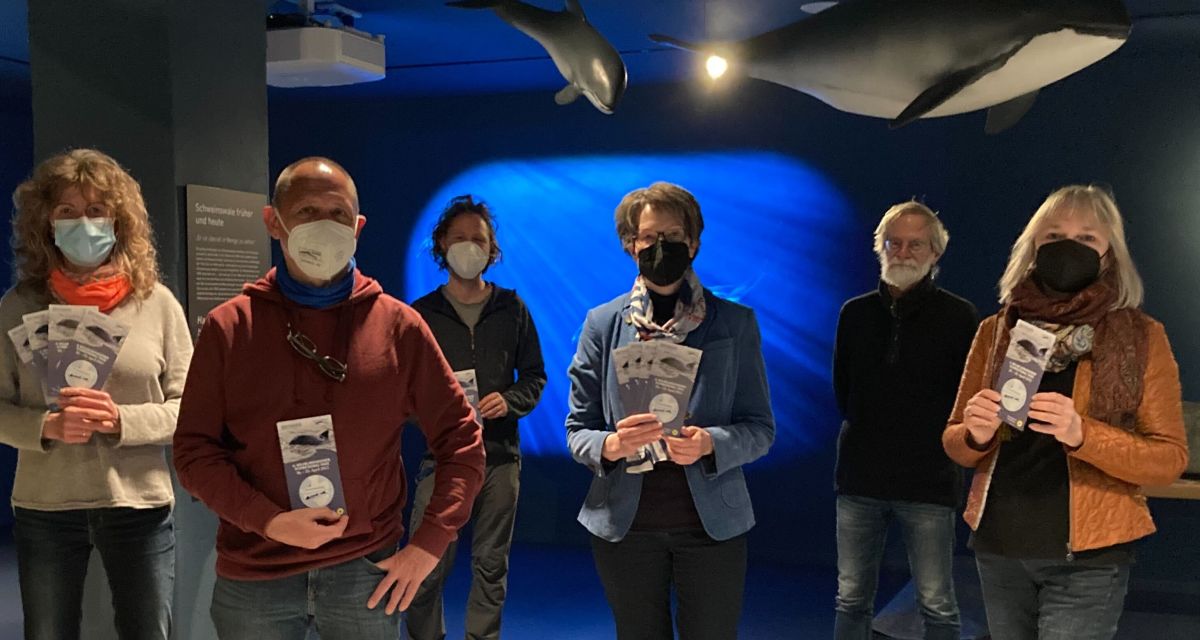 Auf dem Foto sind die Veranstalter*innen und Partner*innen der sechsten Schweinswaltage in Wilhelmshaven zu sehen. Sie befinden sich in der neuen Walausstellung im Wattenmeer Besucherzentrum.