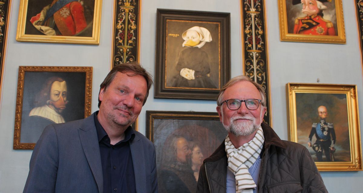 Ommo Wille und Andreas Kreye posieren vor einigen Bildern aus der Ausstellung Duckomenta