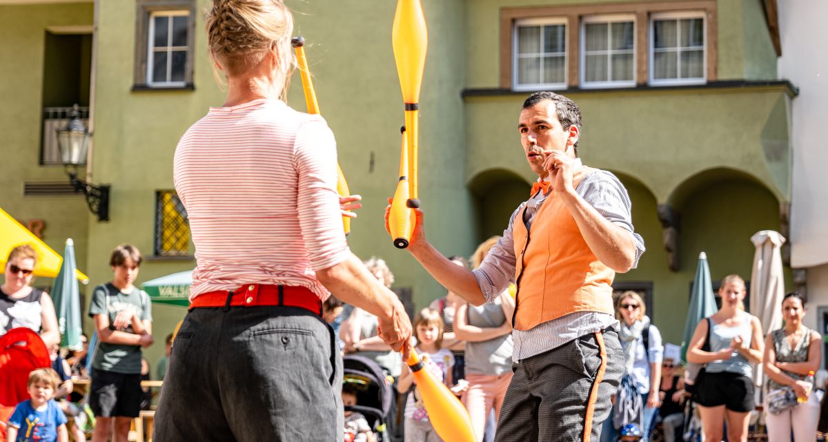 Die Gruppe Chur Clubs wird beim Schortenser Klinkerzauber 2022 auftreten. Das Bild zeigt zwei Menschen bei der Jonglage mit Keulen, um sie herum steht das Publikum.