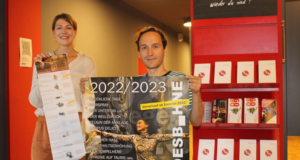 Zu sehen sind Kerstin Car und Robert Teufel von der Landesbühne Niedersachsen Nord mit dem Plakat und Katalog der Spielzeit 2022/23.
