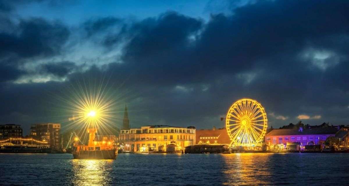 Der Bontekai bei Nacht, beschienen von den Lichtern eines hell erleuchteten Riesenrads.