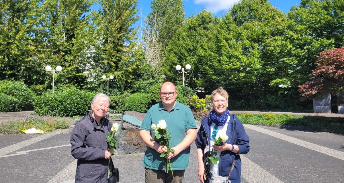 Vertreter*innen der SPD stehen mit weißen Rosen auf dem Synagogenplatz in Wilhelmshaven