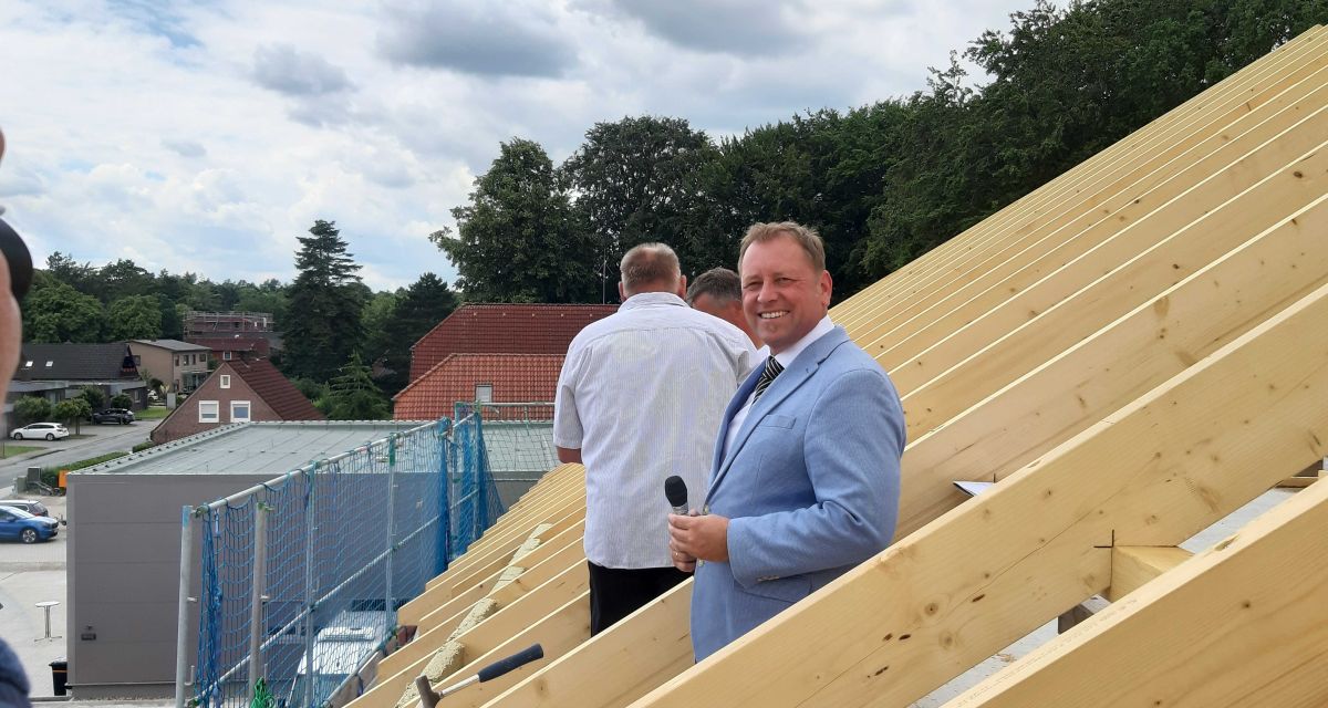 Ein glücklicher und lachender Helfried Goetz steht zwischen zwei Dachbalken des neuen Friedeburger Rathaus.