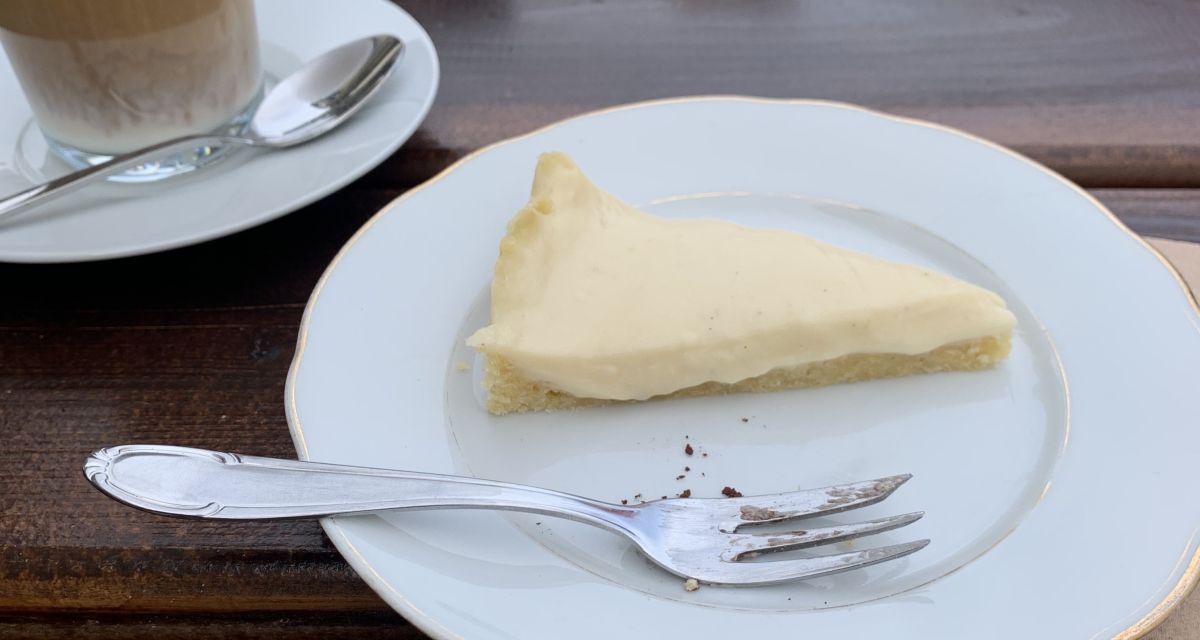 Ein Stück Kuchen und ein latte macchiato auf einem Tisch in einem Café