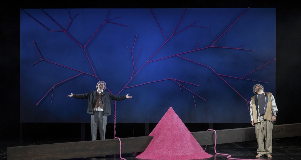 Zwei Schauspieler stehen auf der Bühne, zwischen ihnen ein rosa Stein. 