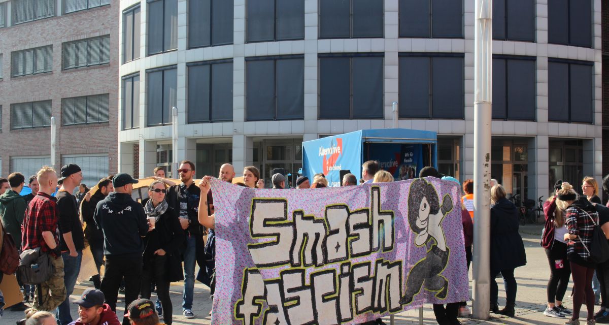 Bühnenwagen der AfD und Gegendemonstranten mit Transparent auf dem Valoisplatz WHV (06.10.18)