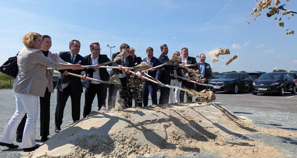 Vertreter*innen aus Politik und Wirtschaft bei Sonnenschein und dem ersten offiziellen Spatenstich für das Projekt