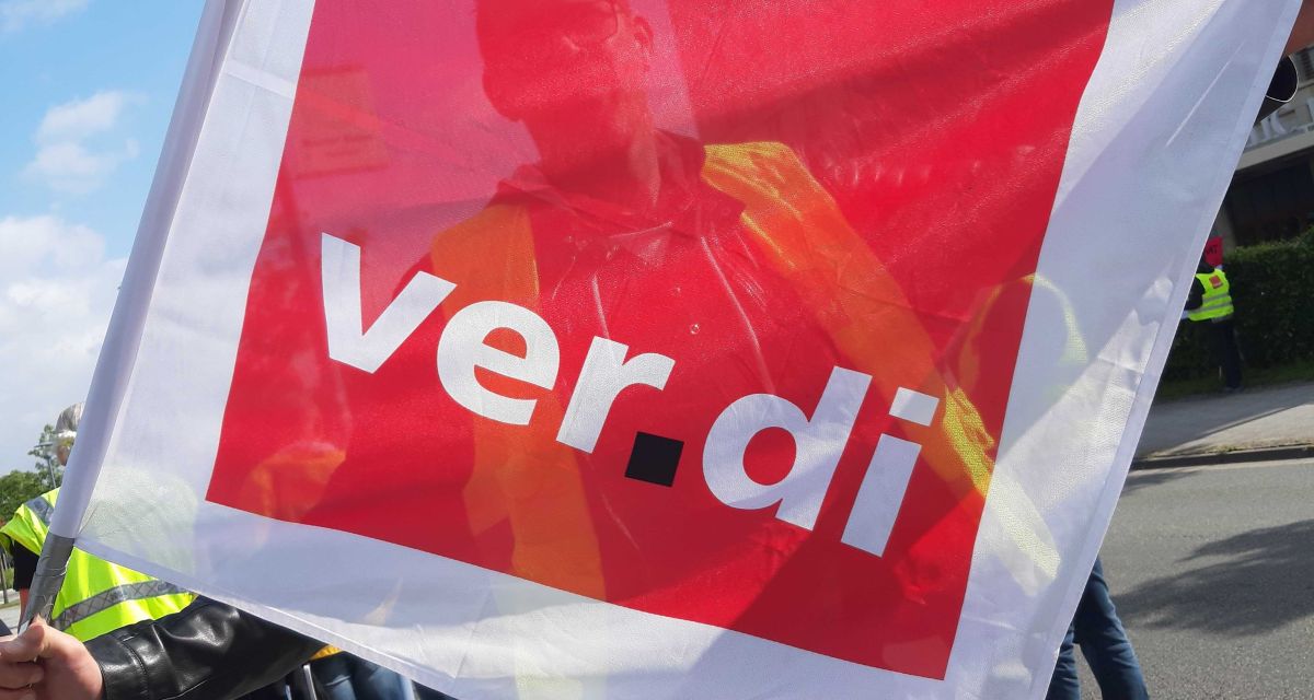 Ein Mann blickt durch eine Ver.Di-Fahne