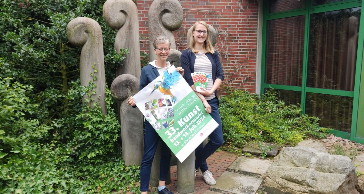 Die Organisator*innen des Kunsthandwerkermarkts in Schortens, unter anderem Bürgerhaus-Leiterin Lotta Klein, präsentieren das Plakat zur Veranstaltung 2024.