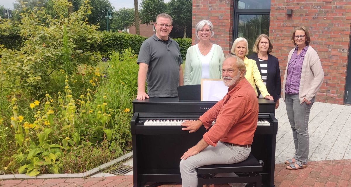 Menschen freuen sich über das neue Piano im Veranstaltungsort