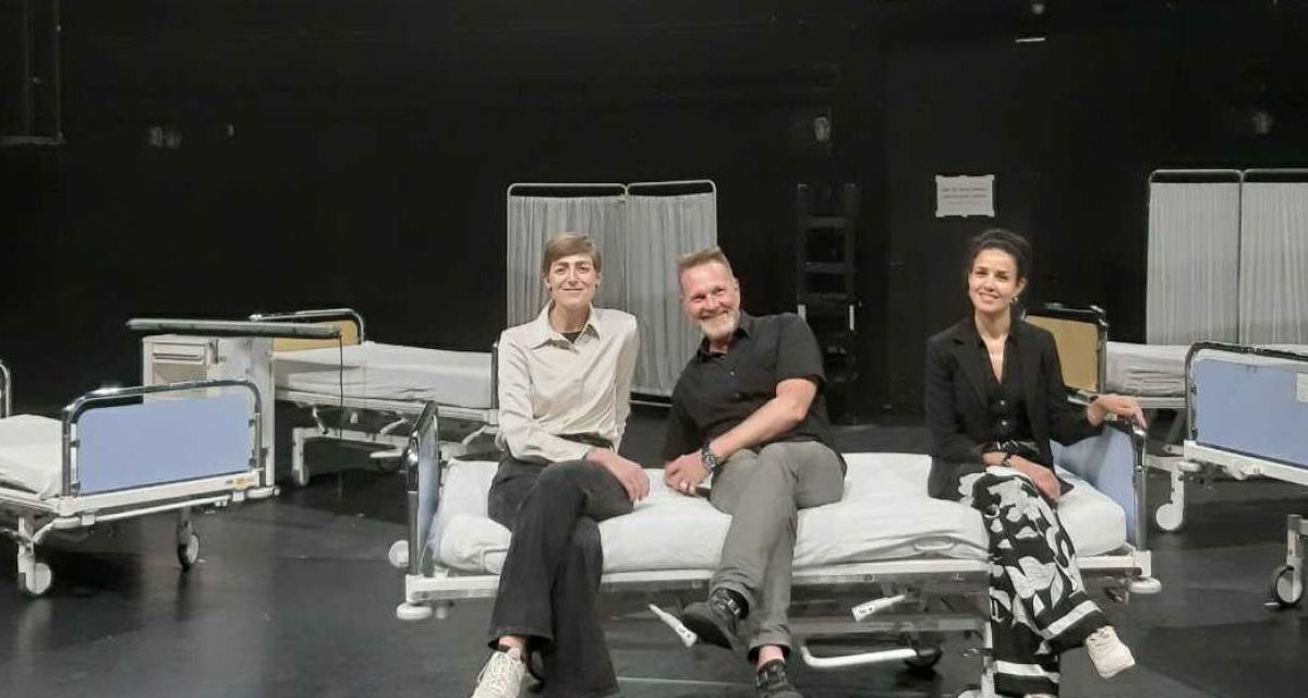 Von links: Kerstin Car, Olaf Strieb, Sarah Helmy
Sie sitzen auf einem Krankenhausbett, das mit weiteren Betten als Bühnenbild/Requisite auf der Bühne steht. Höher im Bühnenbild hängt ein Schild mit der Aufschrift