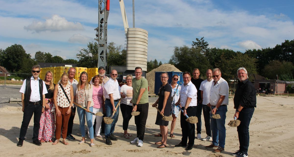 Ein Dutzend menschen mit Spaten auf einer Baustelle