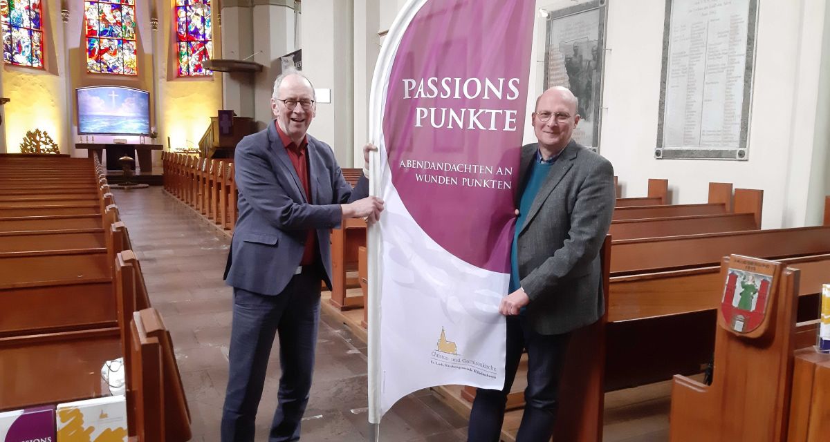 Frank Morgenstern und Bernd Busemann halten im Kirchschiff der Christus- und Garnisonkirche die Beach Flag der Passionspunkte