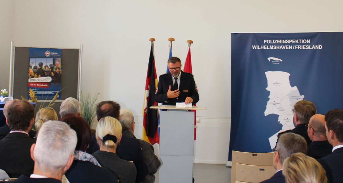 Zu sehen ist Polizeidirektor Jörg Beensen bei seiner Rede anlässlich seiner Amtseinführung. Er steht an einem Pult, während links und rechts Zuhörende zu sehen sind.