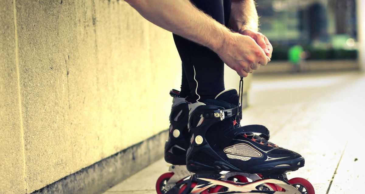 Zu sehen ist ein Paar Inline Skates, die gebunden werden.
