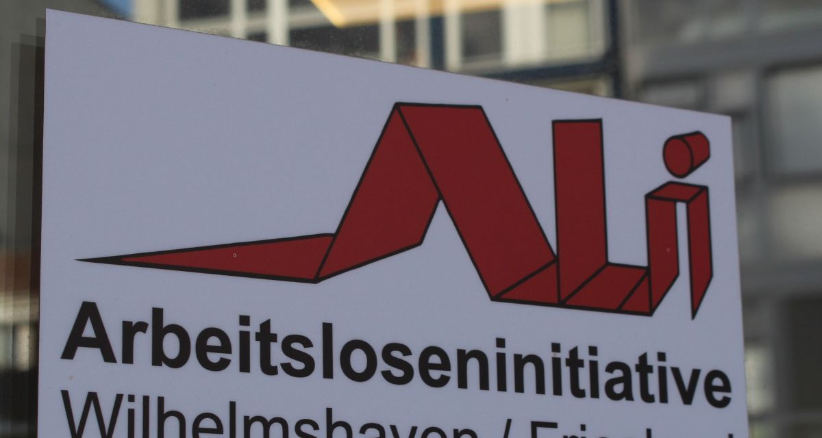 Der Schriftzug der Arbeitsloseninitiative Wilhelmshaven/Friesland auf einer Glasscheibe