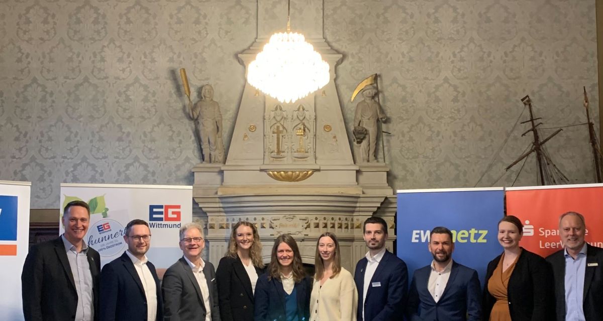 Auf dem Foto sind Vertreter*innen des Landkreises Wittmund und der Sponsoren des Nachhaltigkeitspreises vor den Bannern der Sponsoren zu sehen. Von links: Landrat Holger Heymann, Michael Lehmann (Energie Genossenschaft), Mario Baumert und Nele Fleßner (beide Raiffeisen-Volksbank), Elisa Bodenstab (Klimaschutzmanagerin des Landkreis Wittmund), Friederike Fischer (Landkreis), Steffen Wedemeyer (Wirtschaftsförderer beim Landkreis), Gerrit Pruss (EWE Netz), Jessica Zimmermann und Carsten Rinne (beide Sparkasse LeerWittmund).