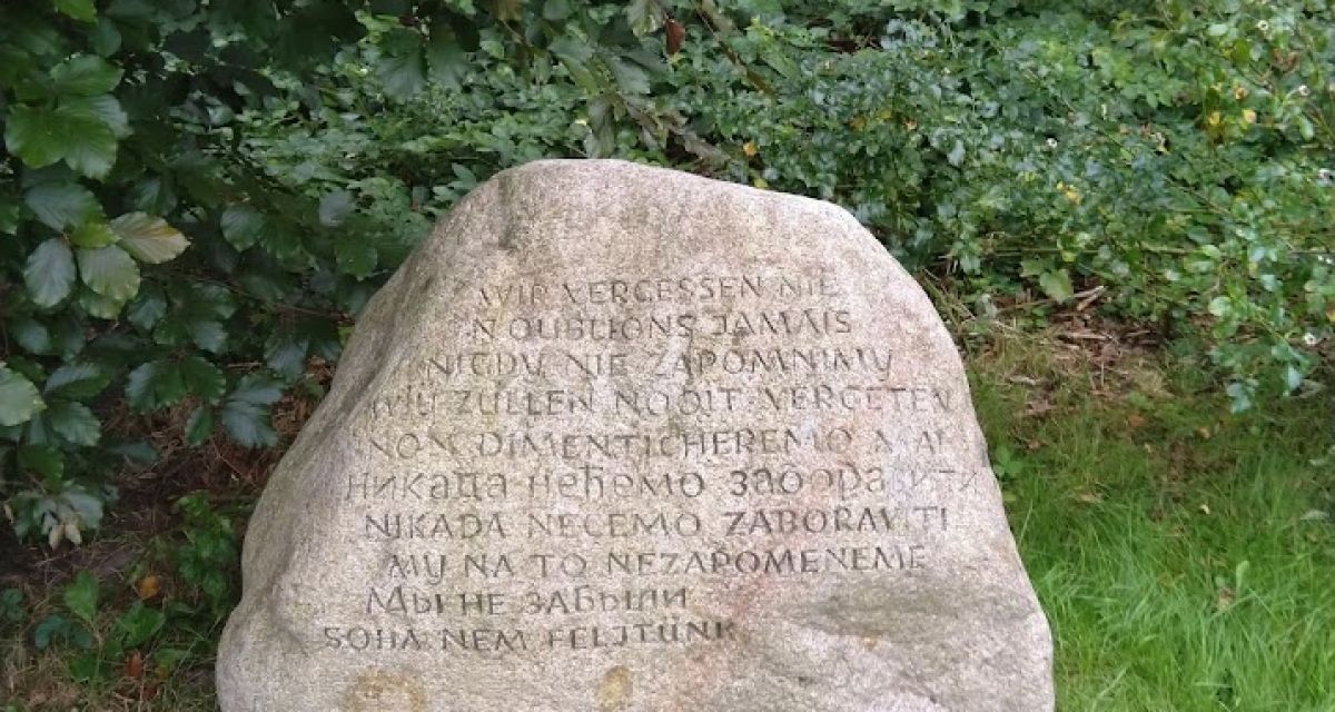 Zu sehen ist ein Gedenkstein auf dem Gelände des ehemaligen Konzentrationslagers Wilhelmshaven. Auf dem großen Fels steht in mehreren Sprachen der Satz 