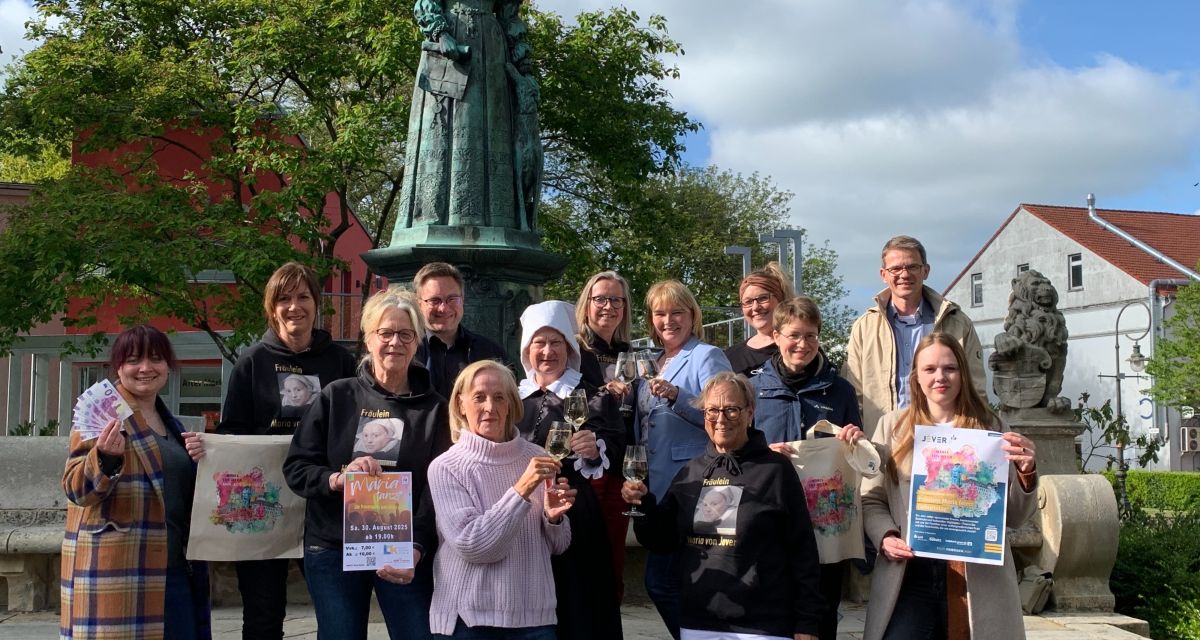 Vor dem Denkmal für Fräulein Maria von Jever haben sich die Verantwortlichen für das Programm im Jubiläumsjahr 2025 versammelt, in der Mitte steht eine Charakter-Darstellerin von