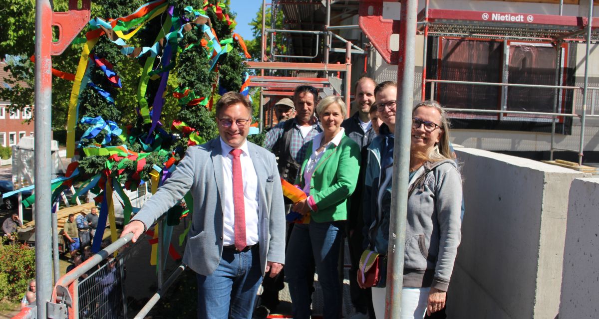 Richtfest des Erweiterungsbaus der Paul-Sillus-Schule in Jever. Auf dem Gerüst vor der Richtkrone steht Bürgermeister Jan Edo Albers mt Vertreter*innen von Stadtpolitik, der Schule und des Handwerks
