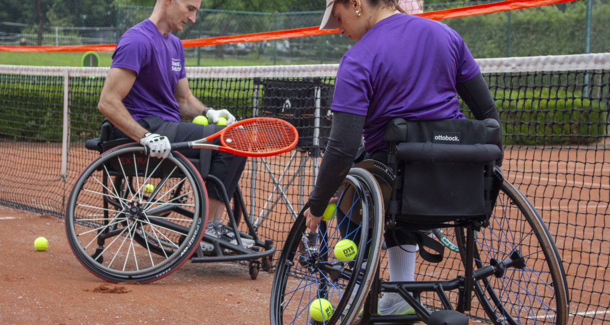 Zwei Teilnehmer sammeln die Tennisbälle auf 