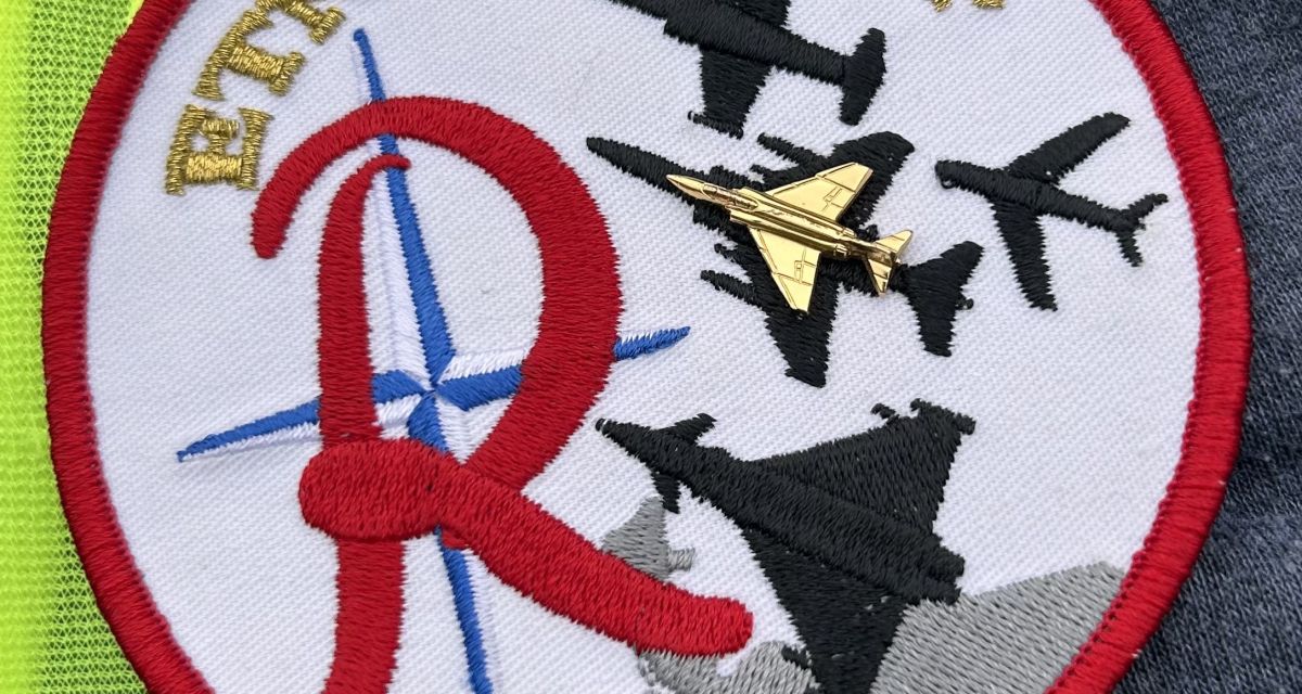 Zusehen ist ein Abzeichen mit Flugzeugen und rotem Buchstaben R