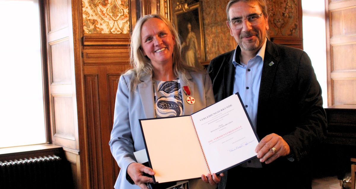Renate-Claudia Brunken wird ihre Verdienstmedaille von Landrat Sven Ambrosy im Schloss Jever überreicht