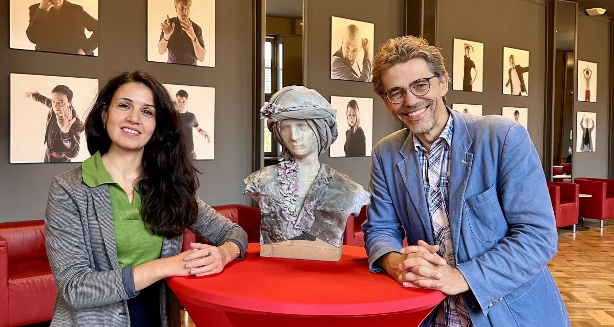 Zu sehen sind Sarah Helmy, Pressesprecherin der Landesbühne und Marcel Krohn, deren Chedramarturg im oberen Foyer des Wilhelmshavener Stadttheaters an eienem Stehtisch.