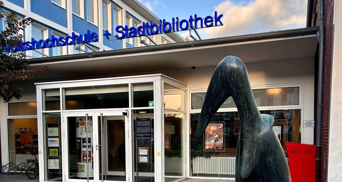 zu sehen ist der Eingang der 1962 gebauten Stadtbücherei, vor der die Skulptur eines Marabus steht.