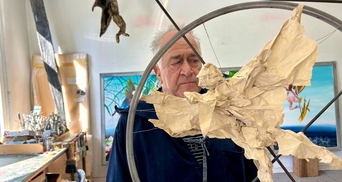 Zu sehen ist de rKünstler im Atelier vor einer Skulptur aus Papier und Metall