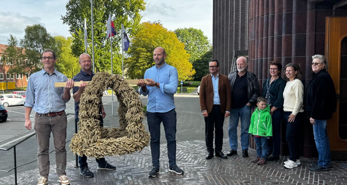 Auf den Treppen des Wilhelmshavener Rathauses übergeben Vertreter des LAndvolkes die Erntekrone an Vertreter:innen der Stadt