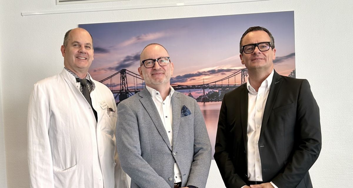 Zu sehen sind vor einem KW-Brücken-Wandbild vlnr: Ärztlicher Direktor Dr. Marcus Schmitt, Geschäftsführer Norman Schaaf und Erster Stadtrat Armin Schönfelder