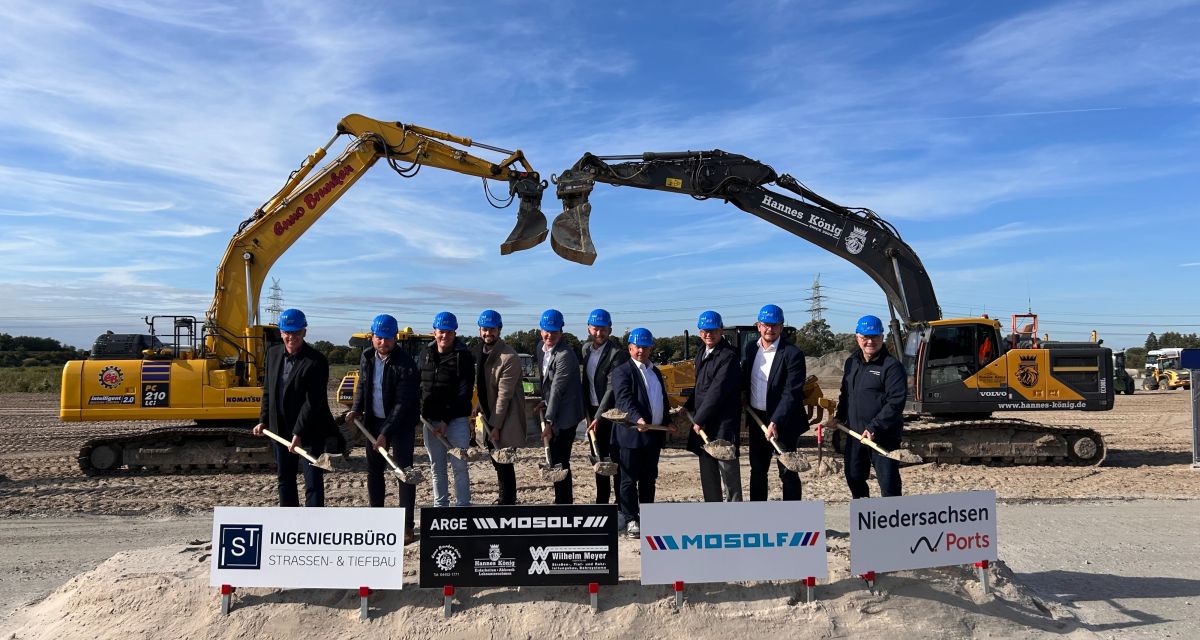 Menschen mit blauen Helmen mit Schaufeln vor Baggern