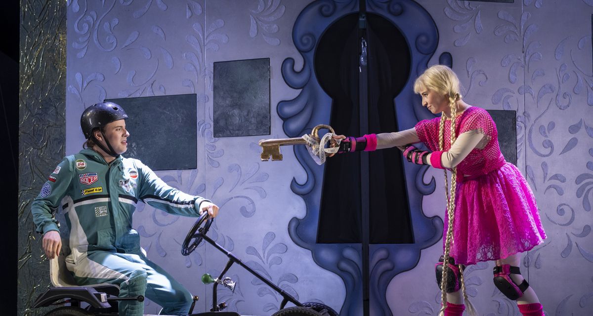 einer sitzt auf einem GoKart, eine zeigt mit einem Schlüssel auf ihn
