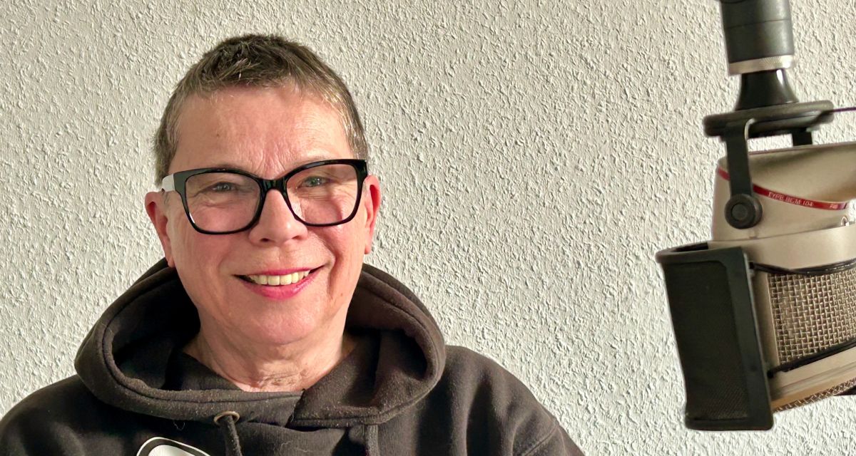Kurzhaarige Frau mit Brille im Hoodie vor dem Mikrofon im Studio