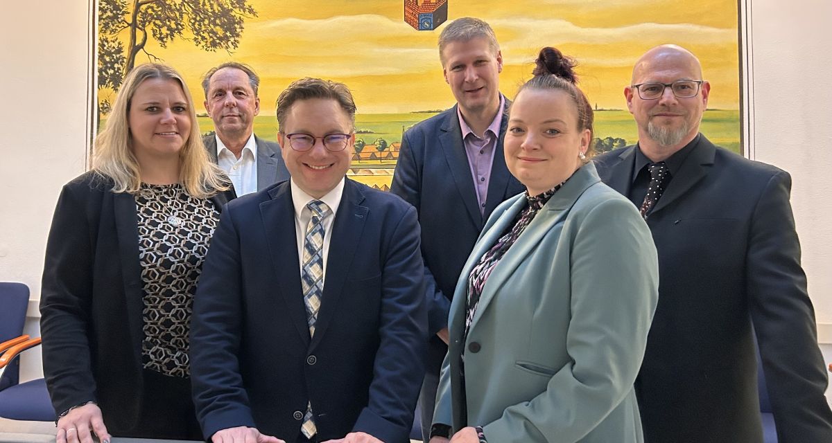 Zu sehen ist Jevers Bürgermeister Jan Edo Albers vor einem Gemälde der Stadt im Kreise seiner Abteilungsleitenden