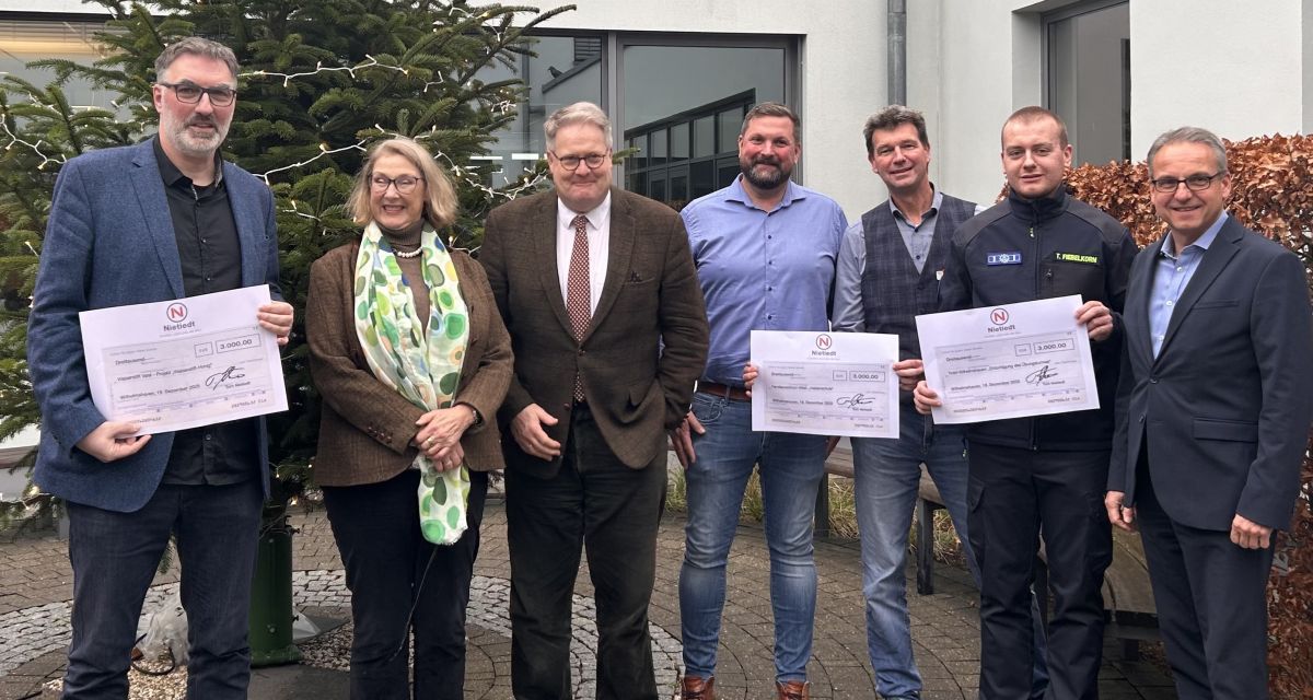 Zu sehen sind Vertreter der Firmengruppe Nietiedt nebst Zuwendungsempfängern der Weihnachtsspende vor einem Weihnachtsbaum