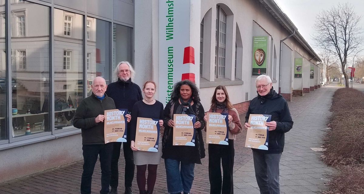 Vertreter*innen des Forums koloniales Erbe Wilhelmshaven präsentieren das Plakat zur Veranstaltungsreihe 
