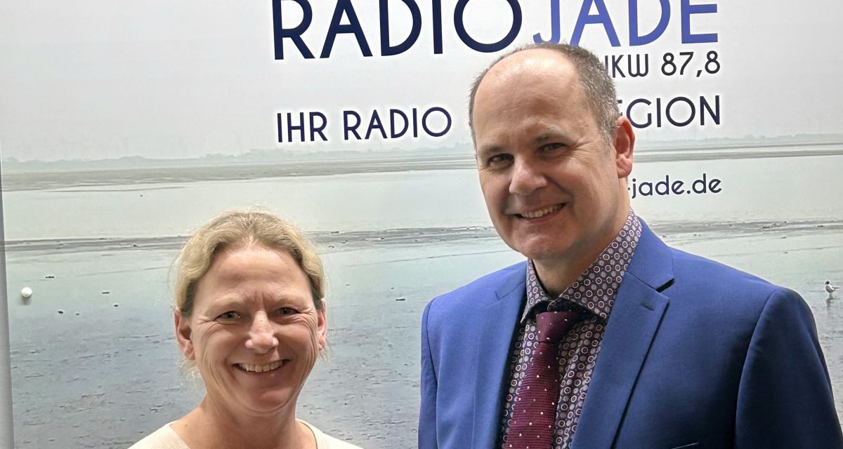 vor dem Radio Jade Logo stehen Frau Dr. Alexandra König und Dr. Marcus Schmitt